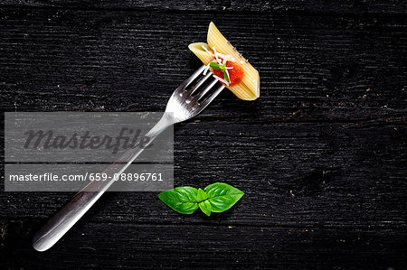 Italian pasta with tomato and basil on fork On wooden board