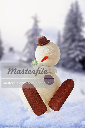 A snowman cake in front of a winter landscape