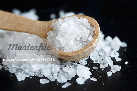 Close up of a heap of coarse salt with a wooden spoon, on black. Close up of a heap of coarse salt with a wooden spoon, on black.