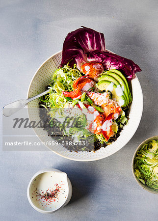 A bowl of wild rice topped with shaved brussel sprouts, avocado slices, lobster meat and a honey lemon buttermilk dressing