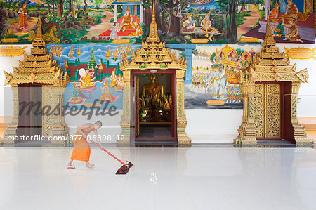 Laos, Vientiane, Buddhist monk cleaning the ground at the entrance of Mixay temple