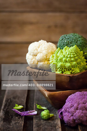 Fresh organic white and purple cauliflower, broccoli, romanesco in wooden bowl