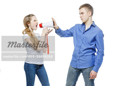 Teen age girl screaming at boy through megaphone. Brother and sister isolated on white background. Copy space.
