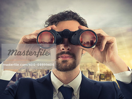 Businessman looks at the city from the roof with binoculars