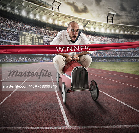 Businessman drives a toy car beyond the red ribbon at the arrival of a race