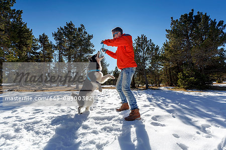 Mature man playing with dog in snow covered forest