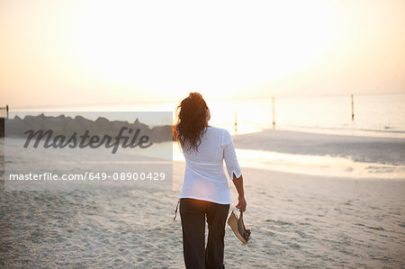 Rear view of woman strolling on beach, Dubai, United Arab Emirates