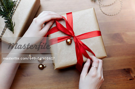 Woman tying red bow on Christmas gift, overhead view