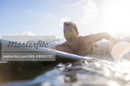 Woman having fun paddling on surfboard in sea, Nosara, Guanacaste Province, Costa Rica