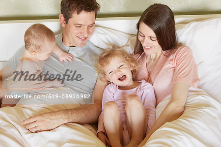 Female toddler and baby sister in bed with parents