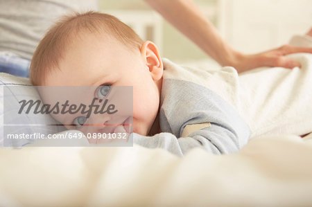 Portrait of baby girl lying on bed with mother