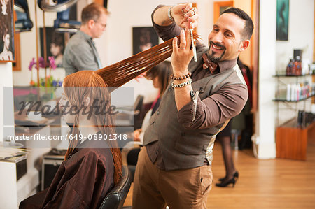 Female customer having long red hair trimmed in hair salon
