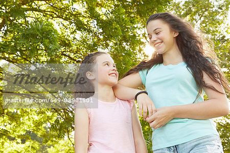 Girl and big sister looking at each other in park