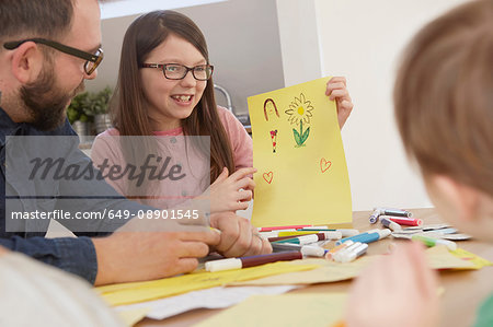 Girl showing brother drawing at table