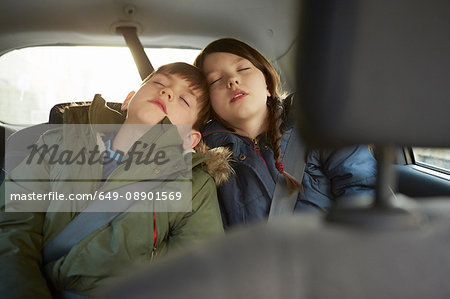 Boy and sister asleep in car backseat