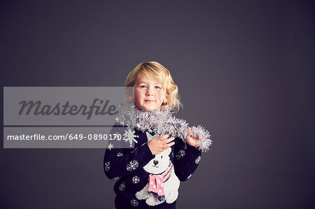 Portrait of young girl wearing Christmas jumper and tinsel around neck