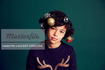 Portrait of teenage boy wearing Christmas jumper, and baubles in hair