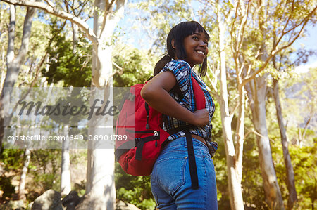 Young woman hiking through forest, looking over shoulder, smiling, Cape Town, South Africa
