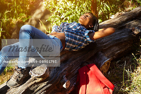 Young woman lying on fallen tree, Cape Town, South Africa