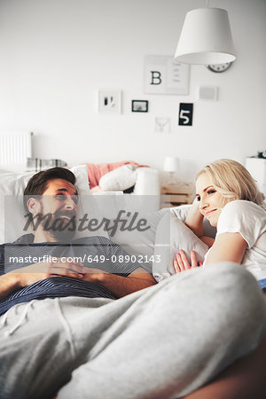 Couple relaxing on bed, smiling