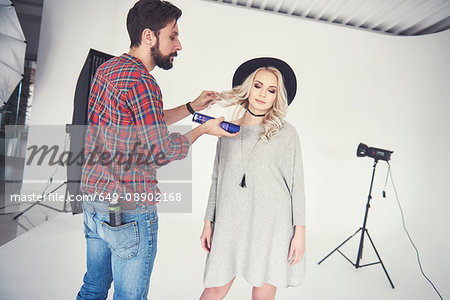 Male photographer adjusting female model's hair on studio white background