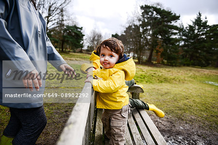 Baby boy with mother in yellow anorak on park bench