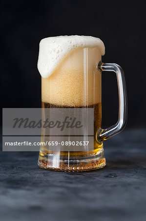 A glass of beer with overflowing foam A glass of beer with overflowing foam