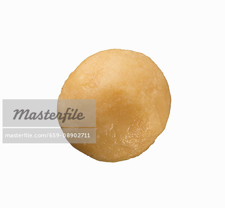 A shelled macadamia nut on white surface