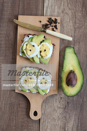 Slices of bread topped with avocado, egg and peppercorns