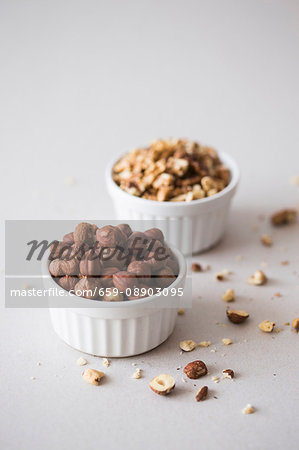 Hazelnuts and walnuts in two white ceramic bowls