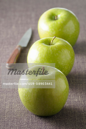 Three green apples on grey tablecloth