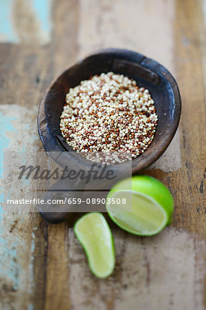 Coloured quinoa in a wooden bowl with a lime next to it