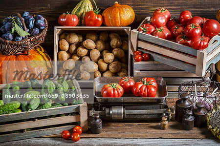 Various types of vegetables in crates and in a basket with plums
