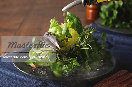 Olive oil being poured over iceberg lettuce