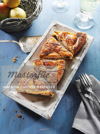 Four slices of pear cake in a wooden dish on a blue wooden table