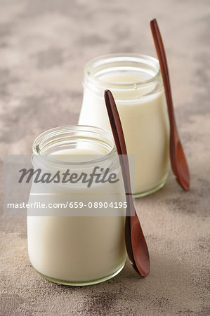 Two glasses of natural yoghurt with wooden spoons