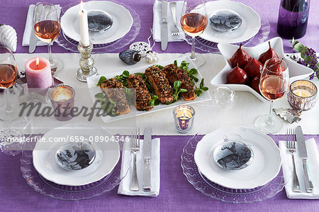 A table late for Christmas in purple with various dishes and glasses of rosé wine