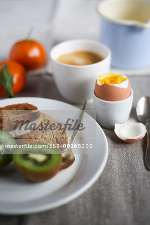 Breakfast with a soft boiled egg, fresh fruit, toast and coffee