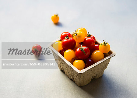 Red and yellow cherry tomatoes in a cardboard container