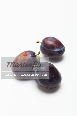 Three damsons on a white surface Three damsons on a white surface
