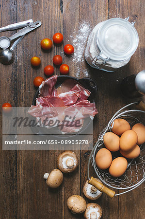 An arrangement of ingredients for tomato quiche with ham and mushrooms