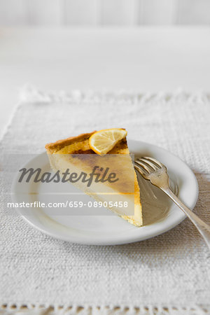 A slice of lemon tart on a plate with a fork A slice of lemon tart on a plate with a fork