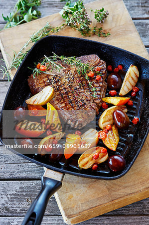 A T-bone steak wth glazed fruits and pumpkin in a grill pan