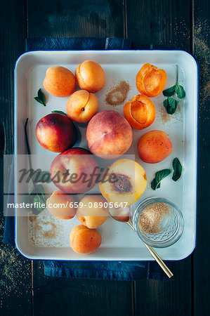 Fruits with stones (apricots, peaches and nectarines) with brown sugar and mint leaves on a tray Fruits with stones (apricots, peaches and nectarines) with brown sugar and mint leaves on a tray