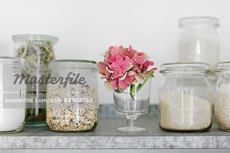 Storage jars (old preserving jars) with muesli, rice, verbena leaves and flour on a zinc shelf in the kitchen