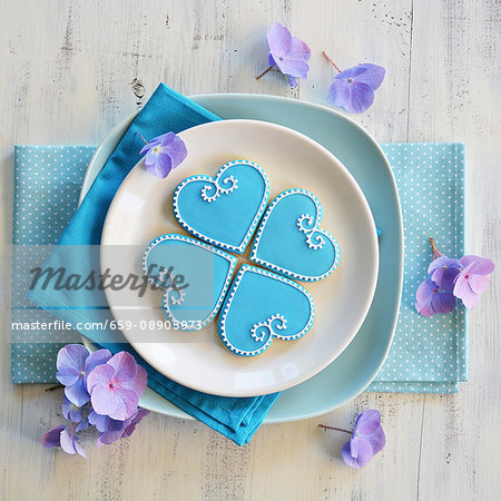 Four heart-shaped biscuits decorated with blue and white icing