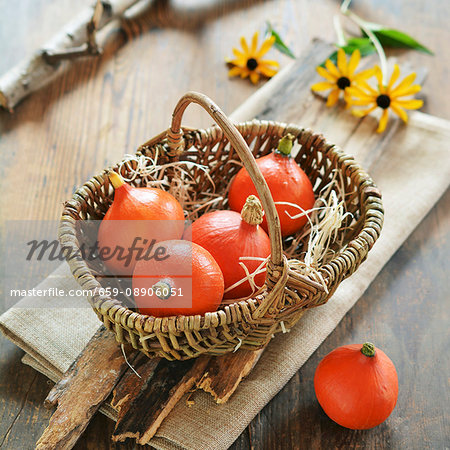 Small hokkaido pumpkins in a basket with flowers in background