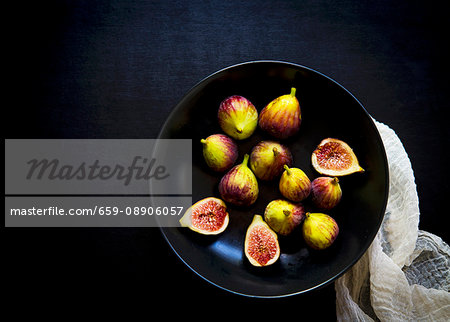 Whole and cut fresh figs in a black bowl Whole and cut fresh figs in a black bowl