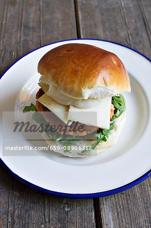 A hamburger with cheese and rocket