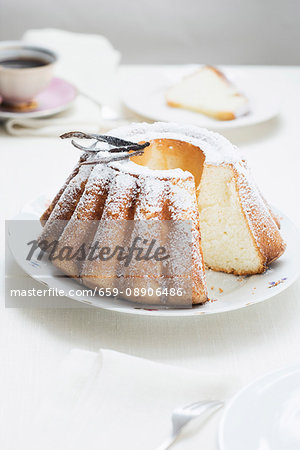 A freshly baked Bundt cake with icing sugar and vanilla pods